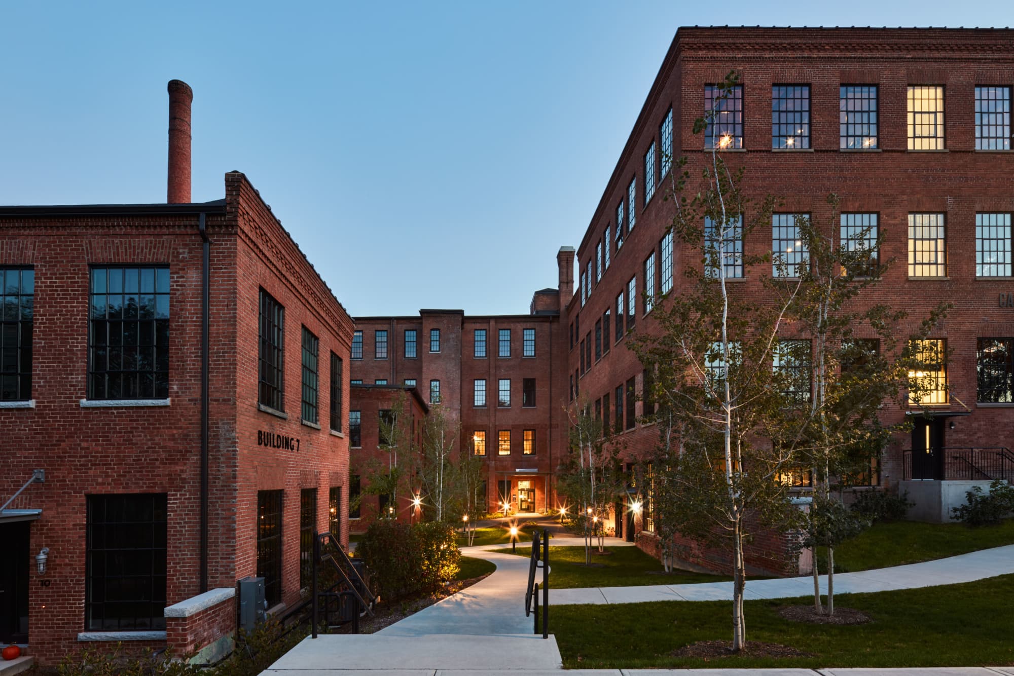 Restored brick mill buildings surrounding a landscaped pedestrian courtyard